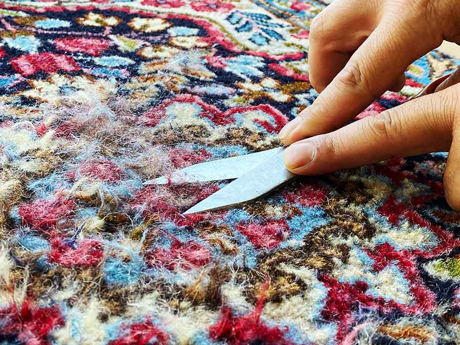Rasatura manuale del tappeto in fase di restauro